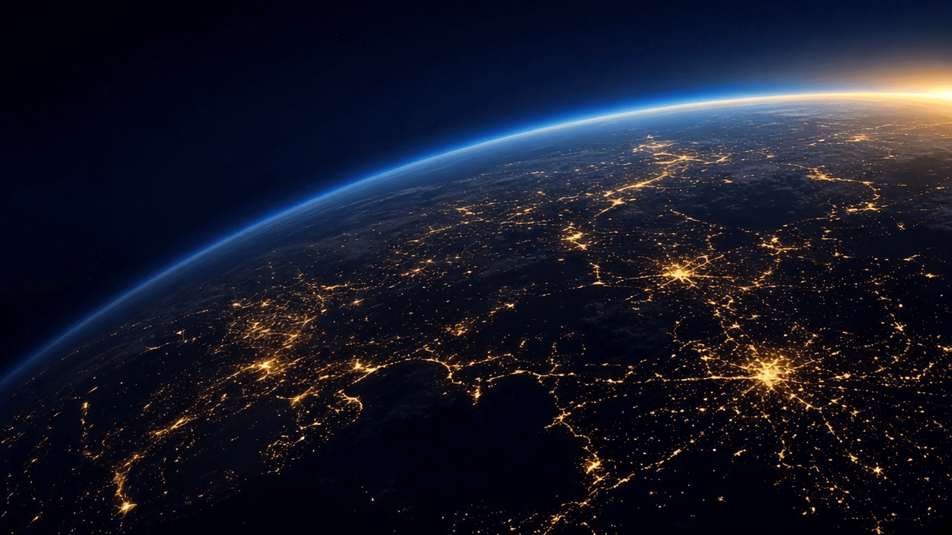 Earth’s night horizon from orbit, city lights glowing along the curve.